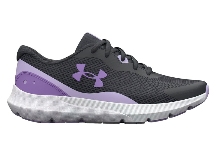 Tenis Under Armour Surge 3 en color gris con detalles morados y suela blanca para niña.