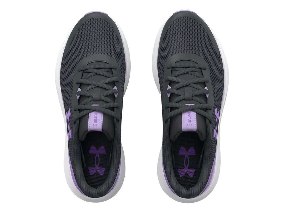 Tenis Under Armour Surge 3 en color gris con detalles morados y suela blanca para niña.