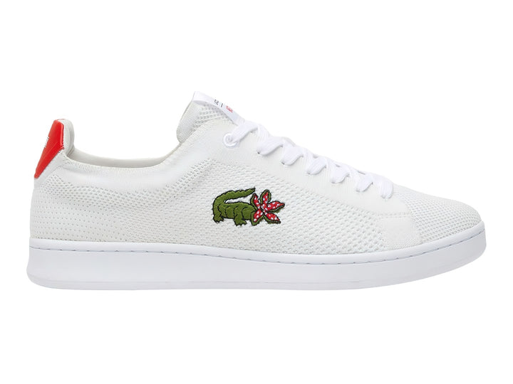Tenis blancos Lacoste de tela con detalle rojo en el talón y logotipo bordado en el costado.