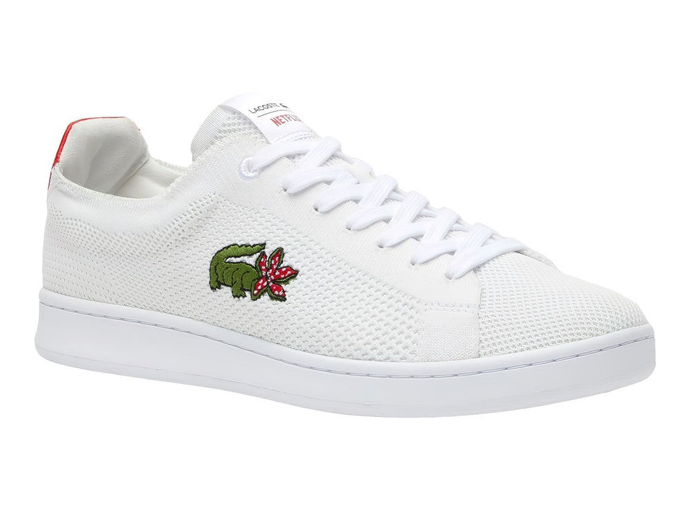 Tenis blancos Lacoste de tela con detalle rojo en el talón y logotipo bordado en el costado.