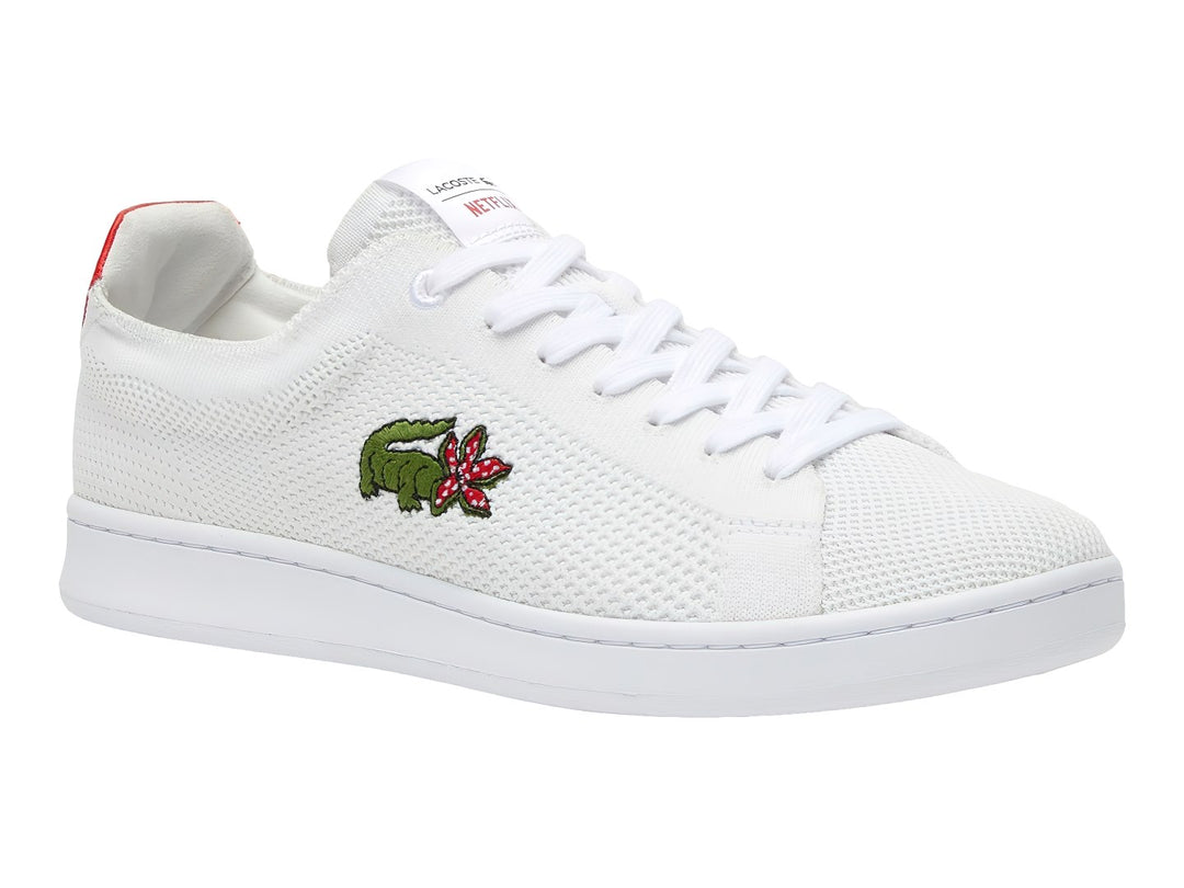 Tenis blancos Lacoste de tela con detalle rojo en el talón y logotipo bordado en el costado.