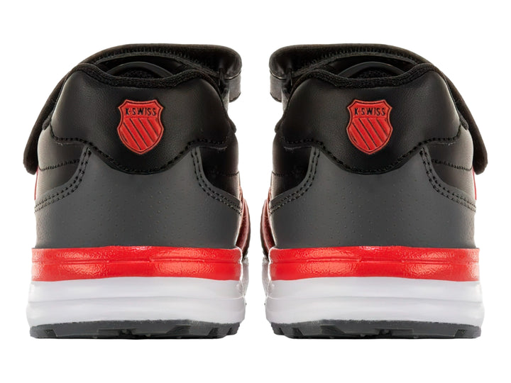 Tenis K-SWISS color negro con franjas rojas laterales, suela blanca y cierre de velcro para niño.