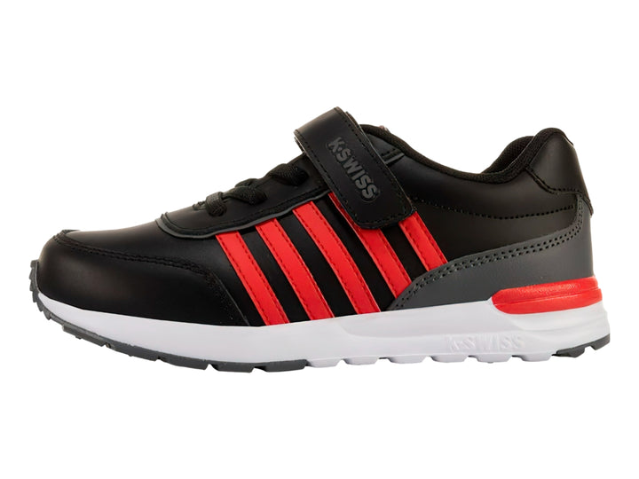 Tenis K-SWISS color negro con franjas rojas laterales, suela blanca y cierre de velcro para niño.