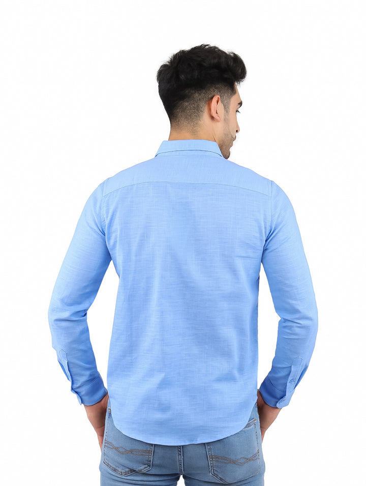 Hombre vistiendo una camisa de lino color azul cielo de manga larga y pantalones vaqueros.