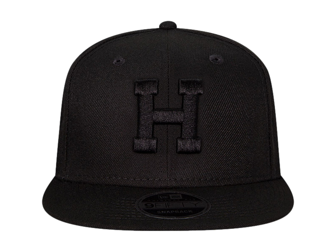 Gorra de béisbol New Era color negro con visera plana y letra H bordada en relieve en el frente.