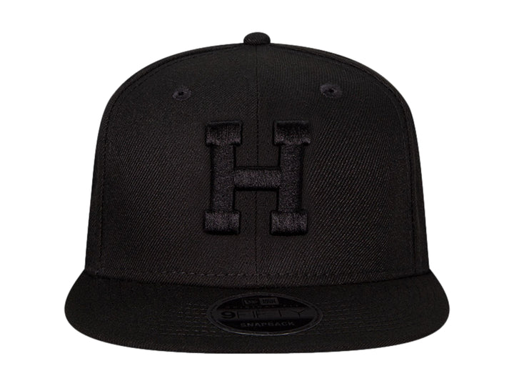 Gorra de béisbol New Era color negro con visera plana y letra H bordada en relieve en el frente.