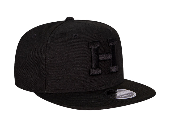 Gorra de béisbol New Era color negro con visera plana y letra H bordada en relieve en el frente.
