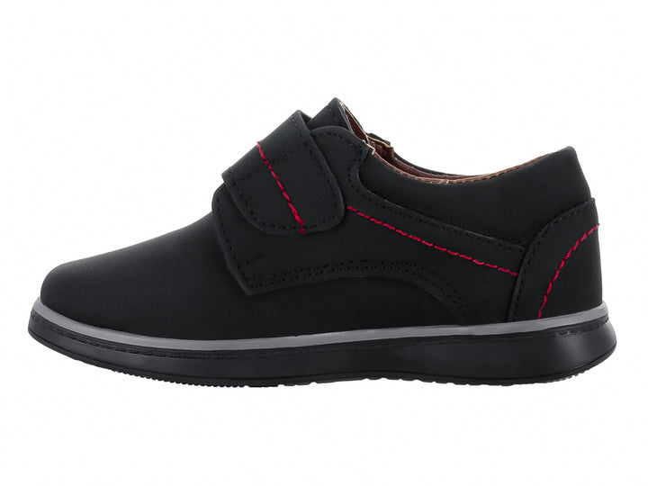 Zapato infantil color negro con costuras rojas y cierre de velcro.