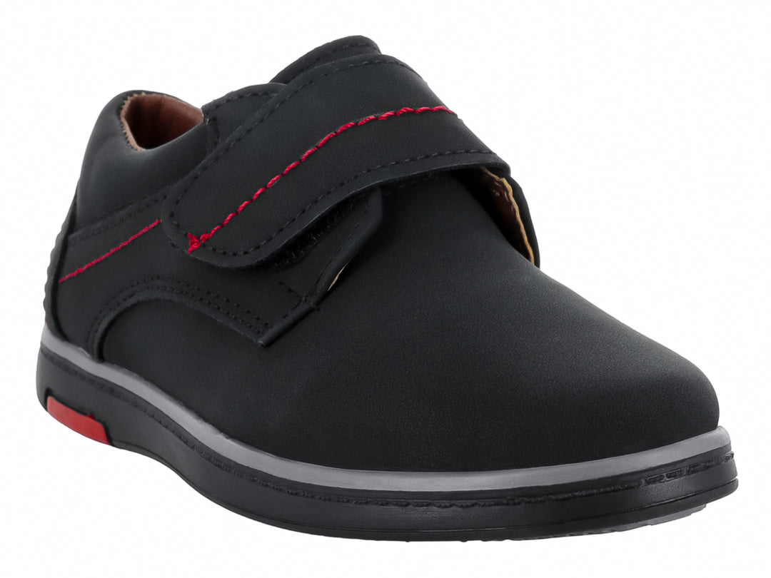 Zapato infantil negro de material nubuck con costuras decorativas en rojo y cierre de velcro.