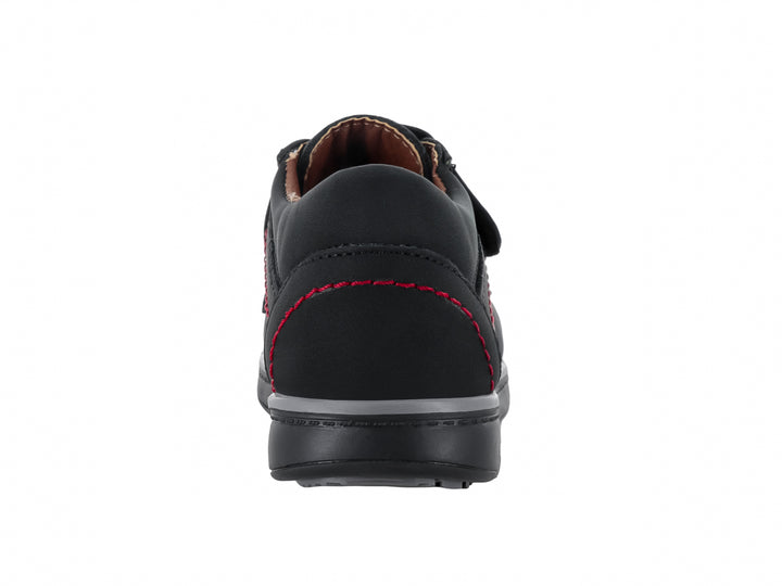 Zapato infantil color negro con costuras rojas y cierre de velcro.