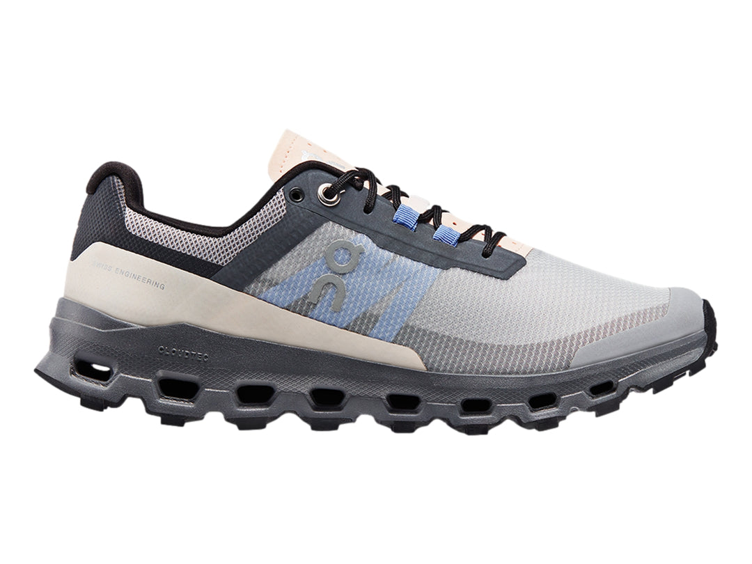 Tenis deportivos On Cloudvista en color gris con detalles azules y suela negra robusta para trail running.