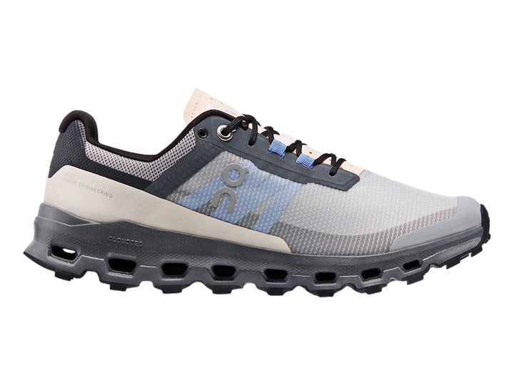 Tenis deportivos On Cloudvista en color gris con detalles azules y suela negra robusta para trail running.