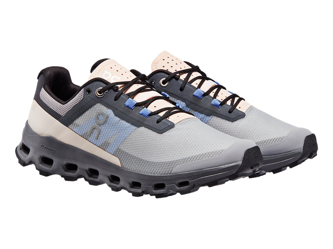 Tenis deportivos On Cloudvista en color gris con detalles azules y suela negra robusta para trail running.