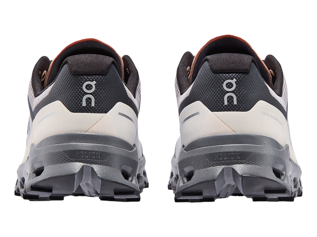 Tenis deportivos On Cloudvista en color gris con detalles azules y suela negra robusta para trail running.