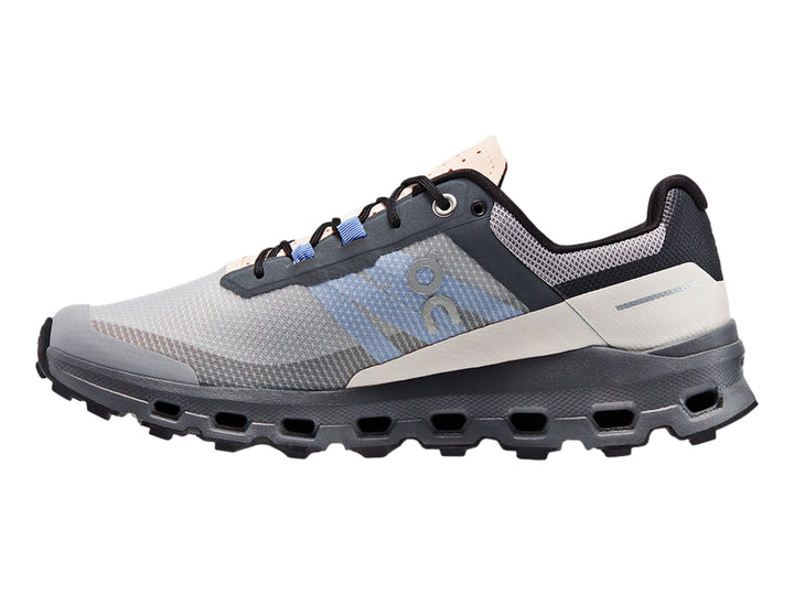 Tenis deportivos On Cloudvista en color gris con detalles azules y suela negra robusta para trail running.
