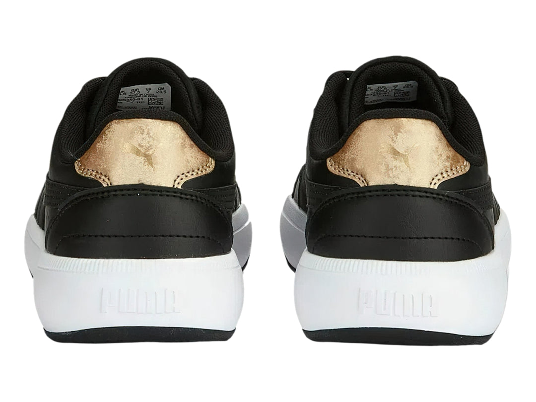 Tenis PUMA negros con suela blanca y detalles dorados en el talón y la lengüeta.