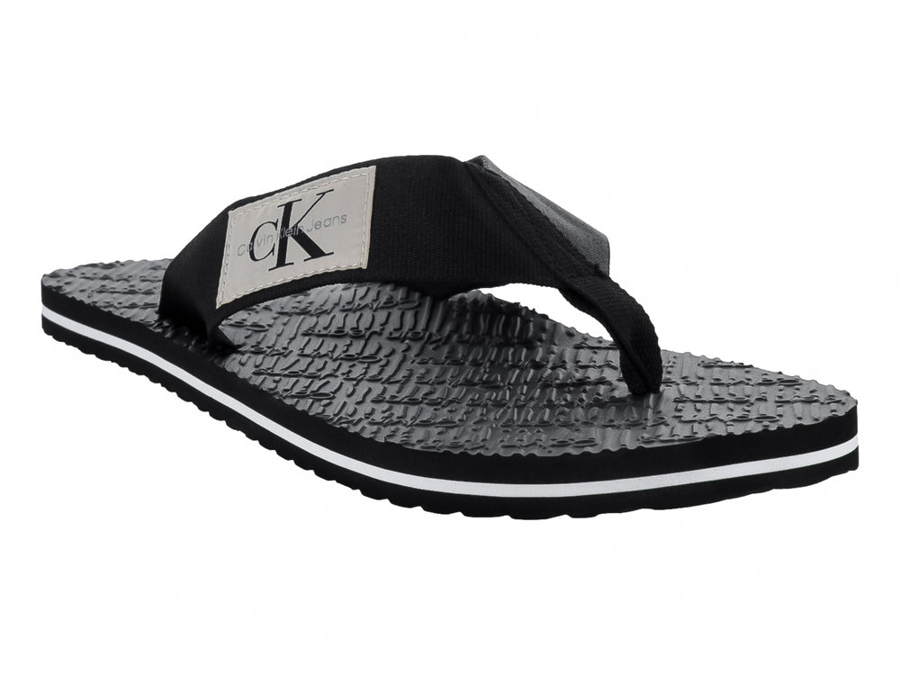 Sandalias flip-flop negras de Calvin Klein con correa de tela y suela texturizada con detalle blanco.