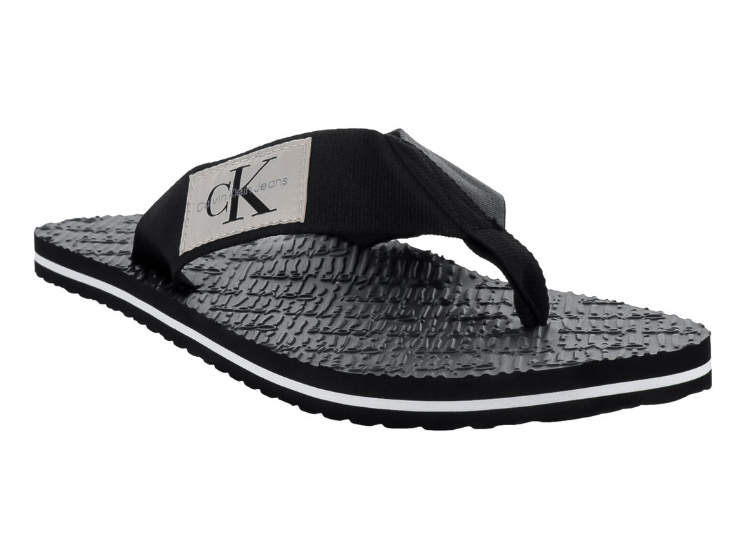 Sandalias flip-flop negras de Calvin Klein con correa de tela y suela texturizada con detalle blanco.