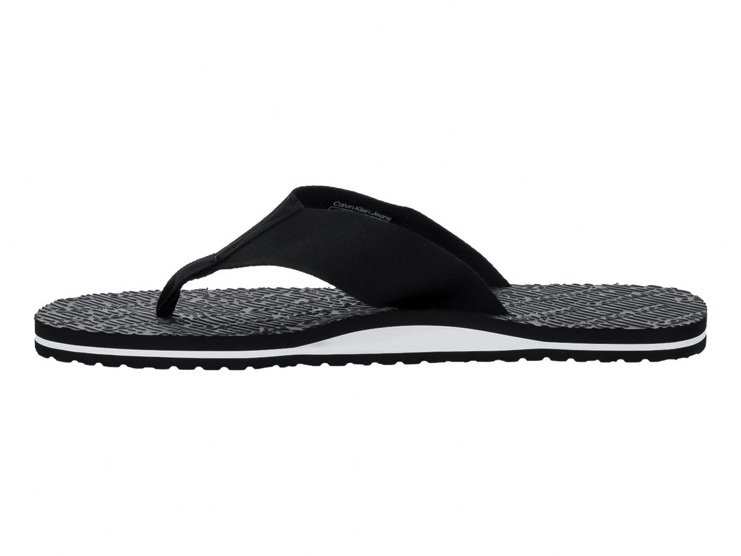 Sandalias flip-flop negras de Calvin Klein con correa de tela y suela texturizada con detalle blanco.