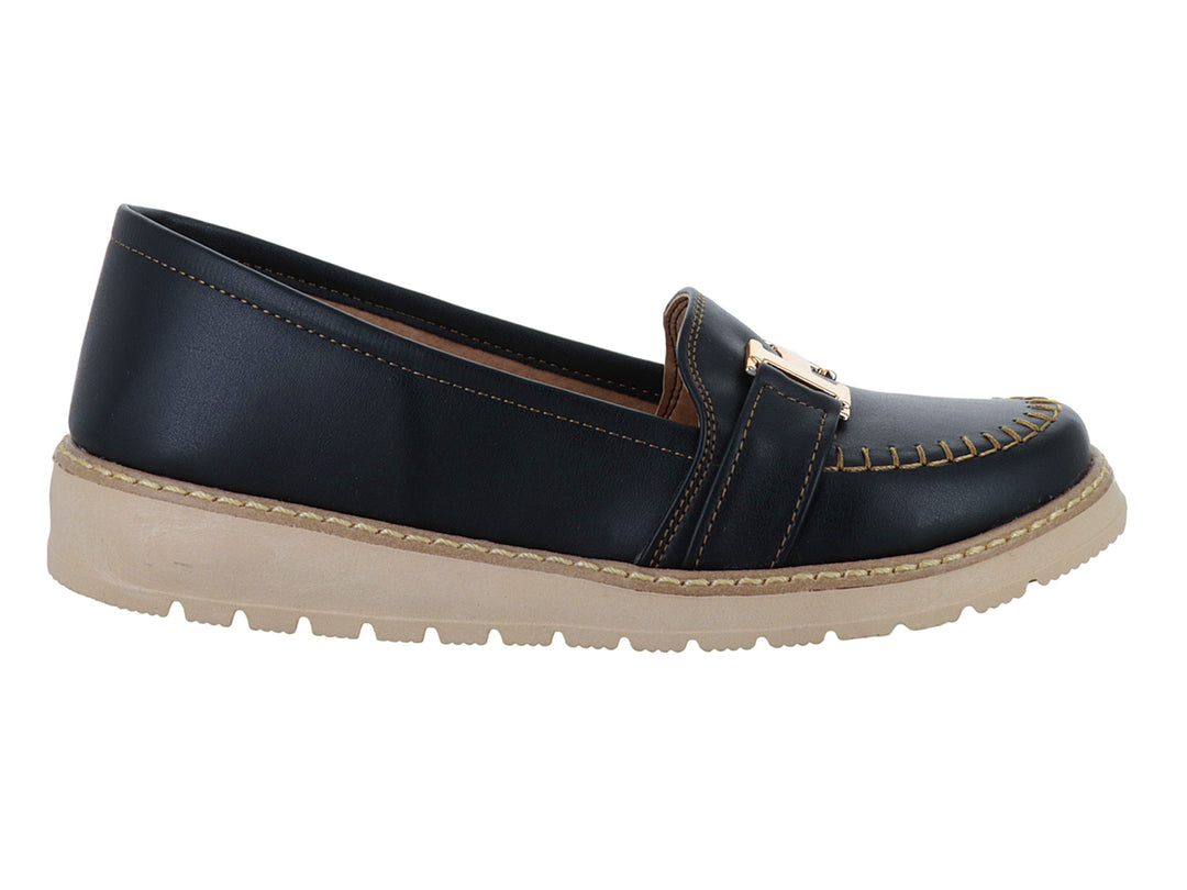 Zapato tipo mocasín color negro con suela gruesa beige y detalle metálico dorado en la parte superior.