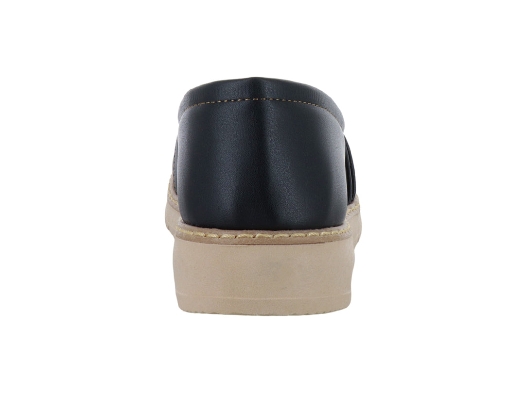 Zapato tipo mocasín color negro con suela gruesa beige y detalle metálico dorado en la parte superior.