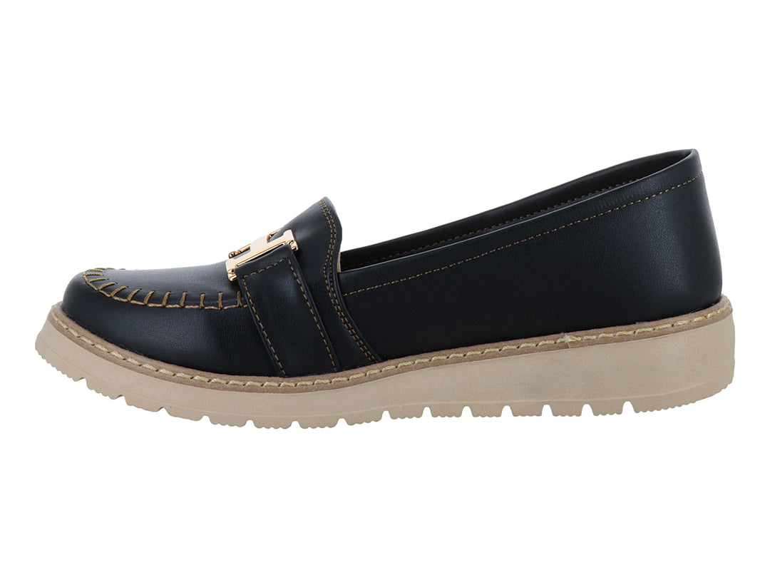 Zapato tipo mocasín color negro con suela gruesa beige y detalle metálico dorado en la parte superior.