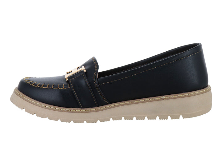 Zapato tipo mocasín color negro con suela gruesa beige y detalle metálico dorado en la parte superior.
