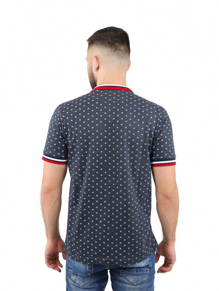 Hombre vistiendo playera polo gris oscuro con estampado pequeño y ribetes rojos y blancos en cuello y mangas.
