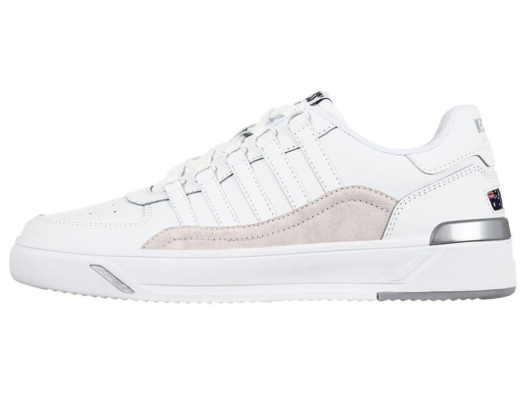 Tenis K-Swiss blancos con franja lateral gris y suela blanca, vista de perfil.