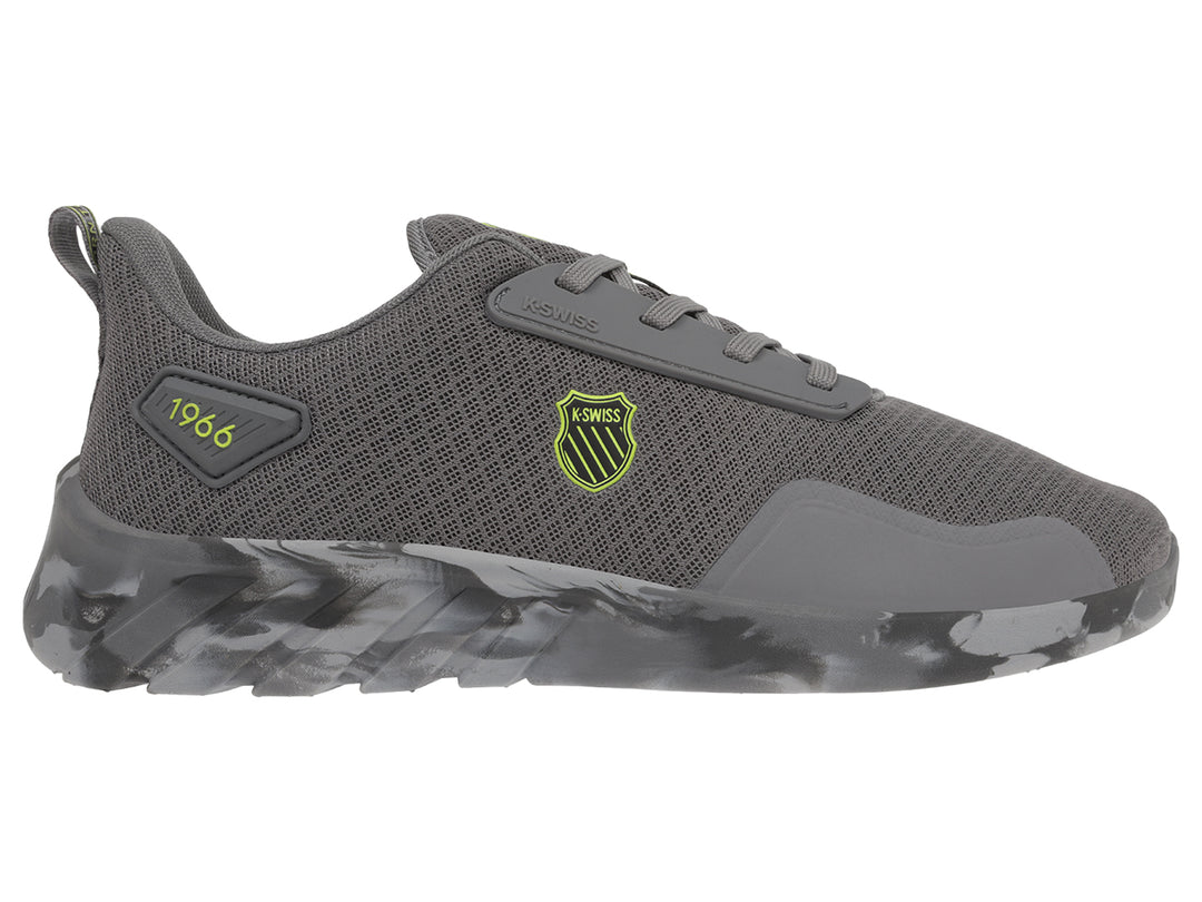 Tenis deportivos K-Swiss color gris con suela en patrón de camuflaje y logotipo amarillo lateral.