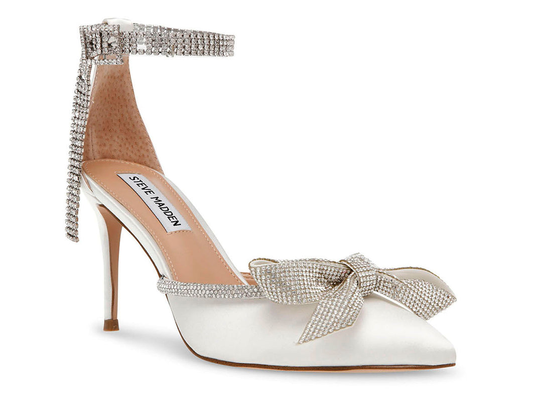 Zapato de tacón Steve Madden en color marfil satinado con detalles de cristales y un moño decorativo en la punta.