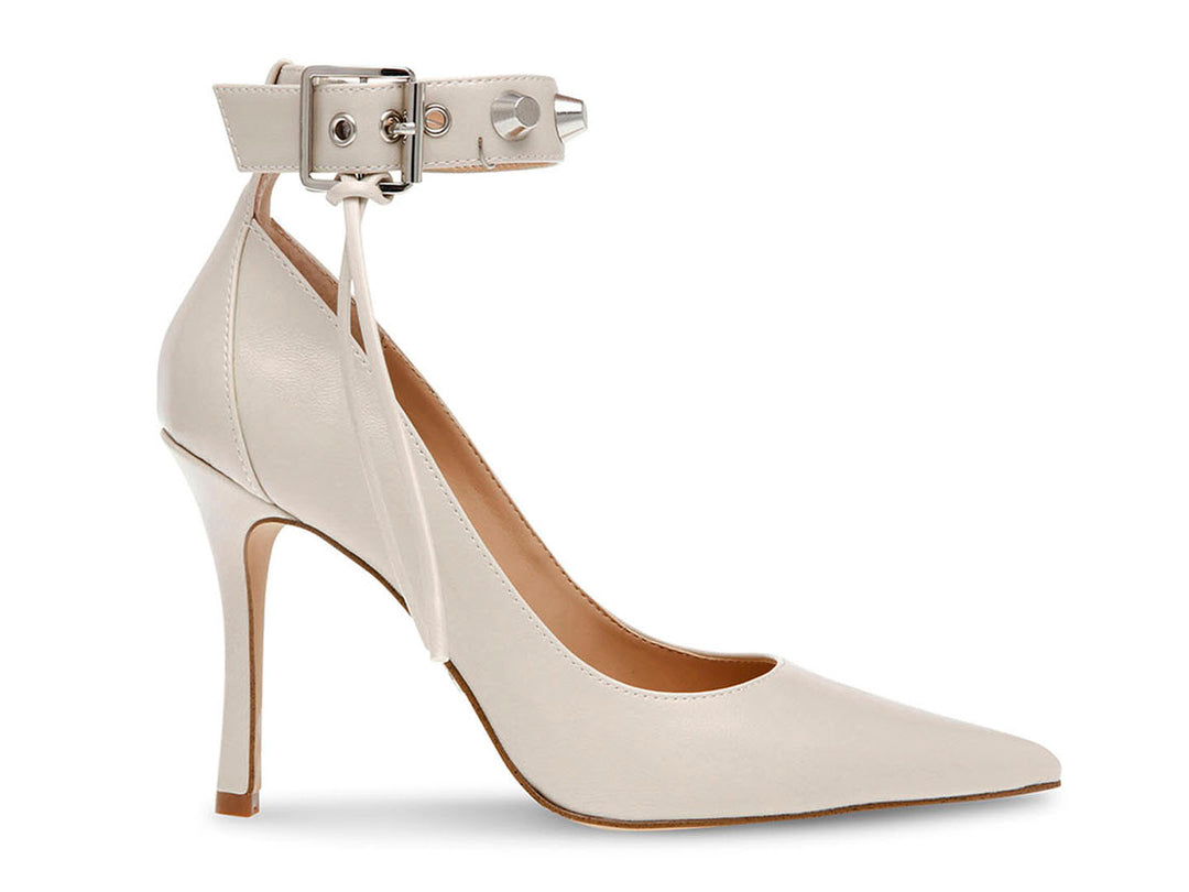 Zapato de tacón stiletto color hueso con punta fina y correa al tobillo decorada con tachuelas.