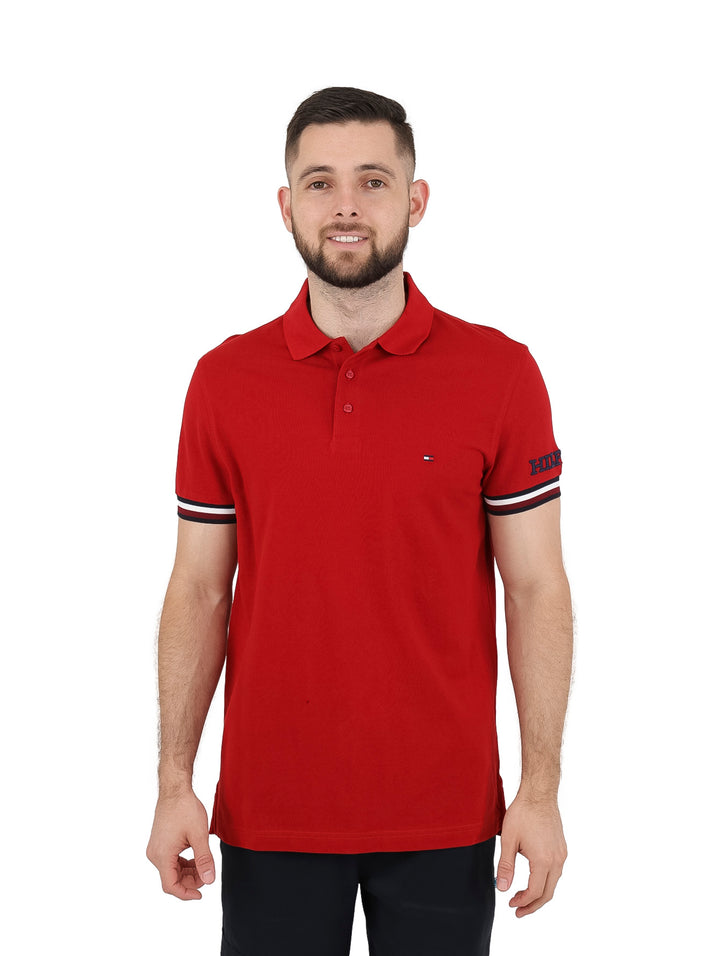 Hombre vistiendo una playera polo Tommy Hilfiger color rojo con detalles blancos en los puños y corte slim fit.