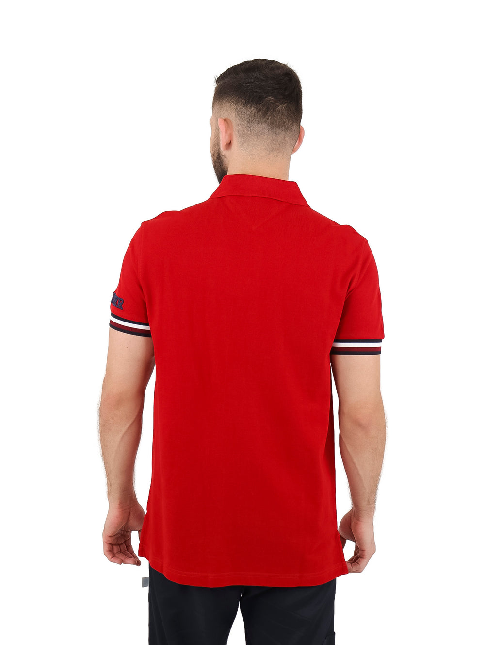 Hombre vistiendo una playera polo Tommy Hilfiger color rojo con detalles blancos en los puños y corte slim fit.