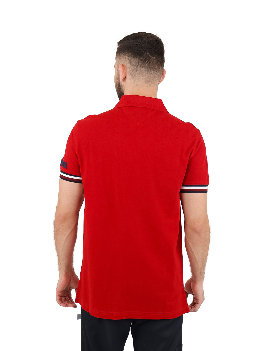 Hombre vistiendo una playera polo Tommy Hilfiger color rojo con detalles blancos en los puños y corte slim fit.