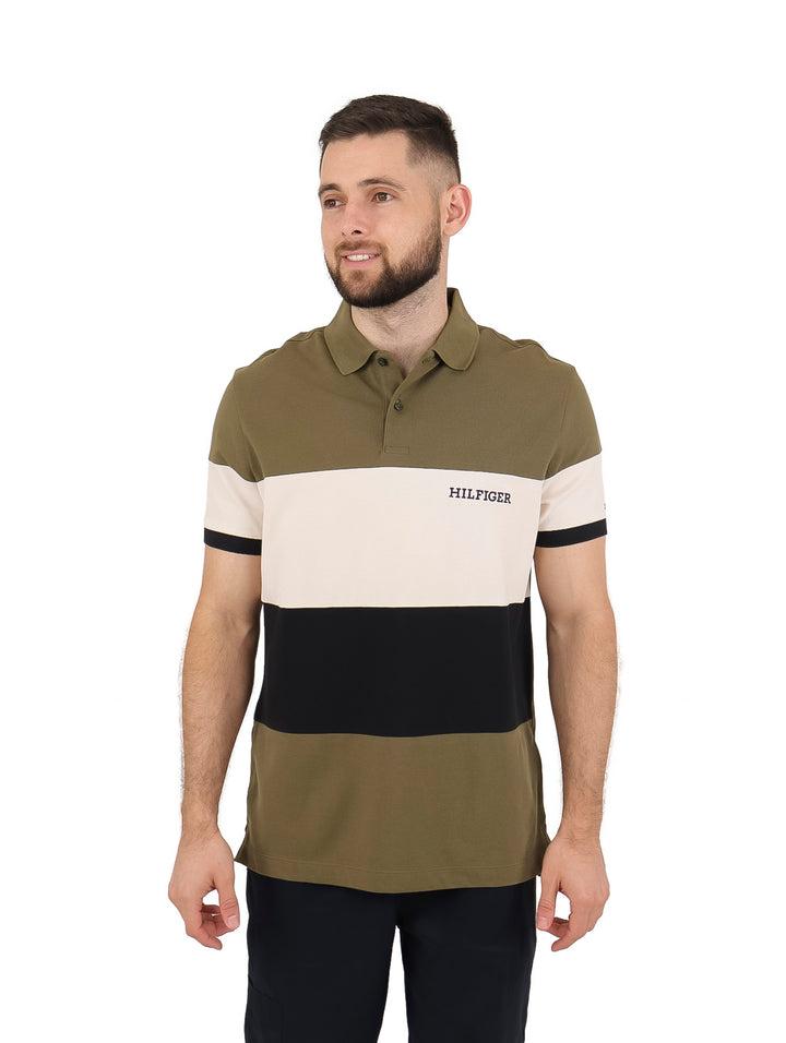 Hombre vistiendo playera polo Tommy Hilfiger con diseño colorblock en verde militar, beige y negro.