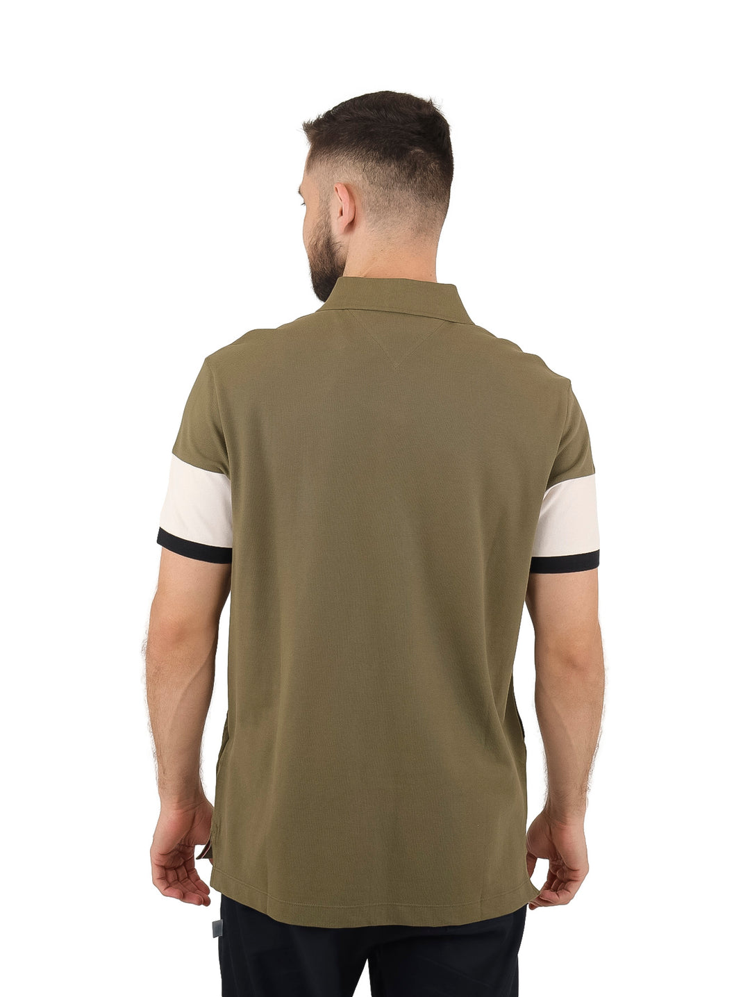 Hombre vistiendo playera polo Tommy Hilfiger con diseño colorblock en verde militar, beige y negro.