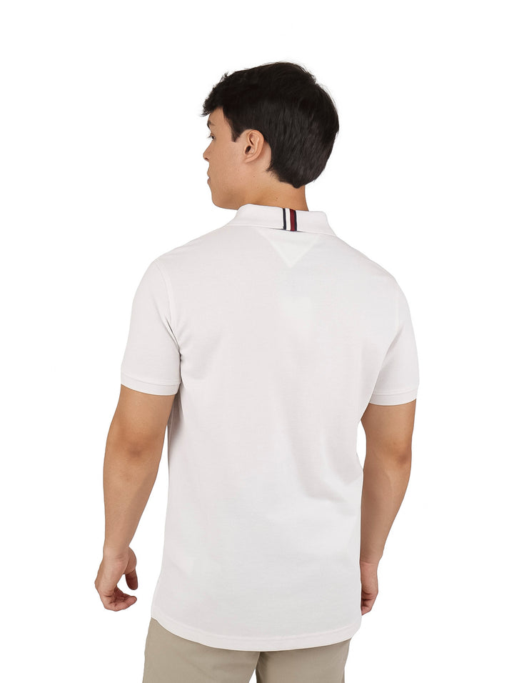 Hombre vistiendo una playera polo de color beige de manga corta con un pequeño logo en el pecho.