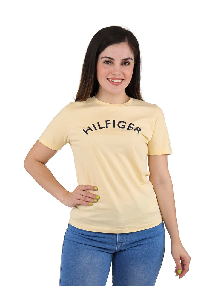 Mujer vistiendo camiseta ajustada color amarillo claro con texto HILFIGER en el pecho.
