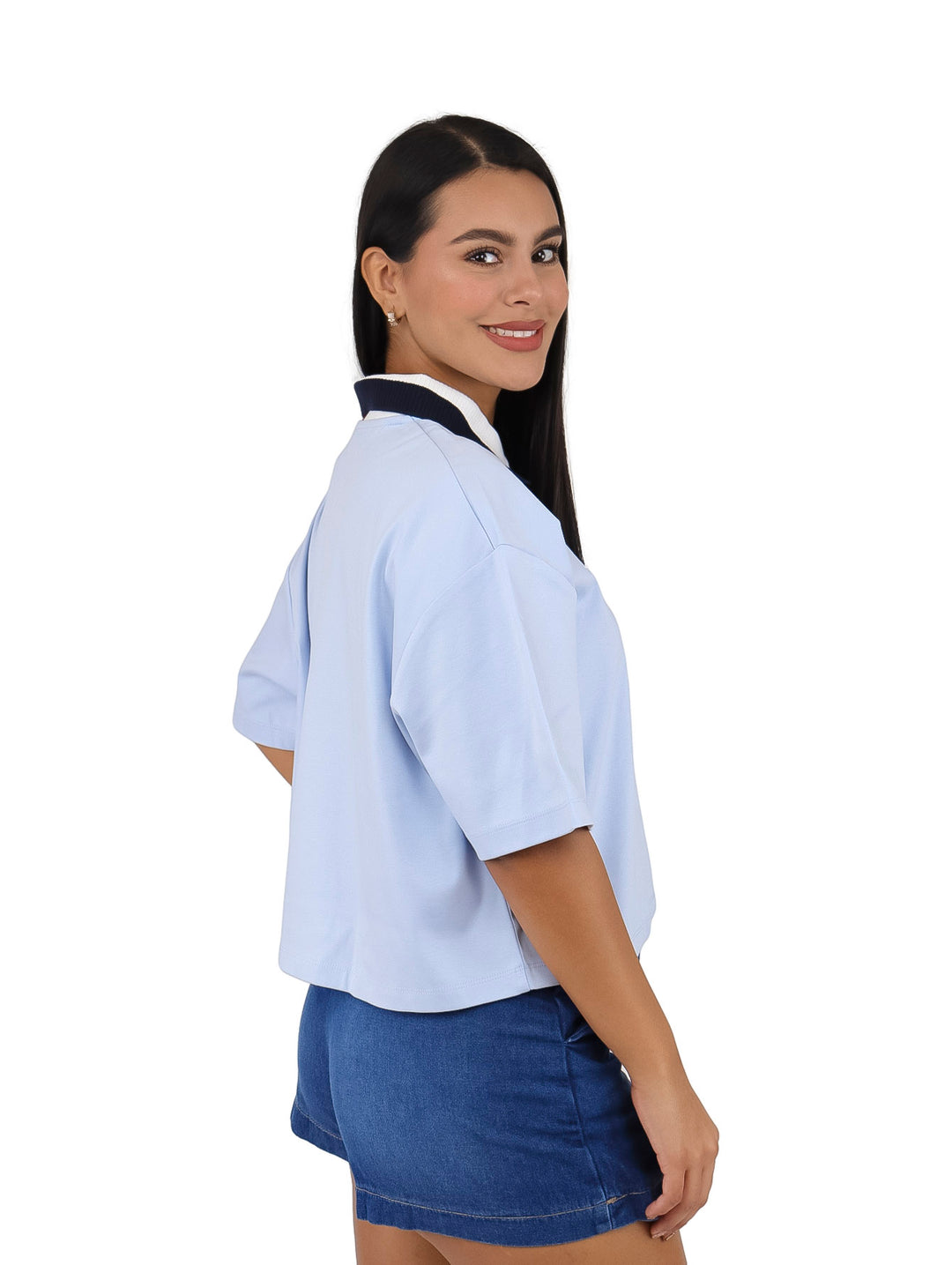 Mujer vistiendo polo crop color azul claro de Tommy Hilfiger con cuello tricolor y falda denim.