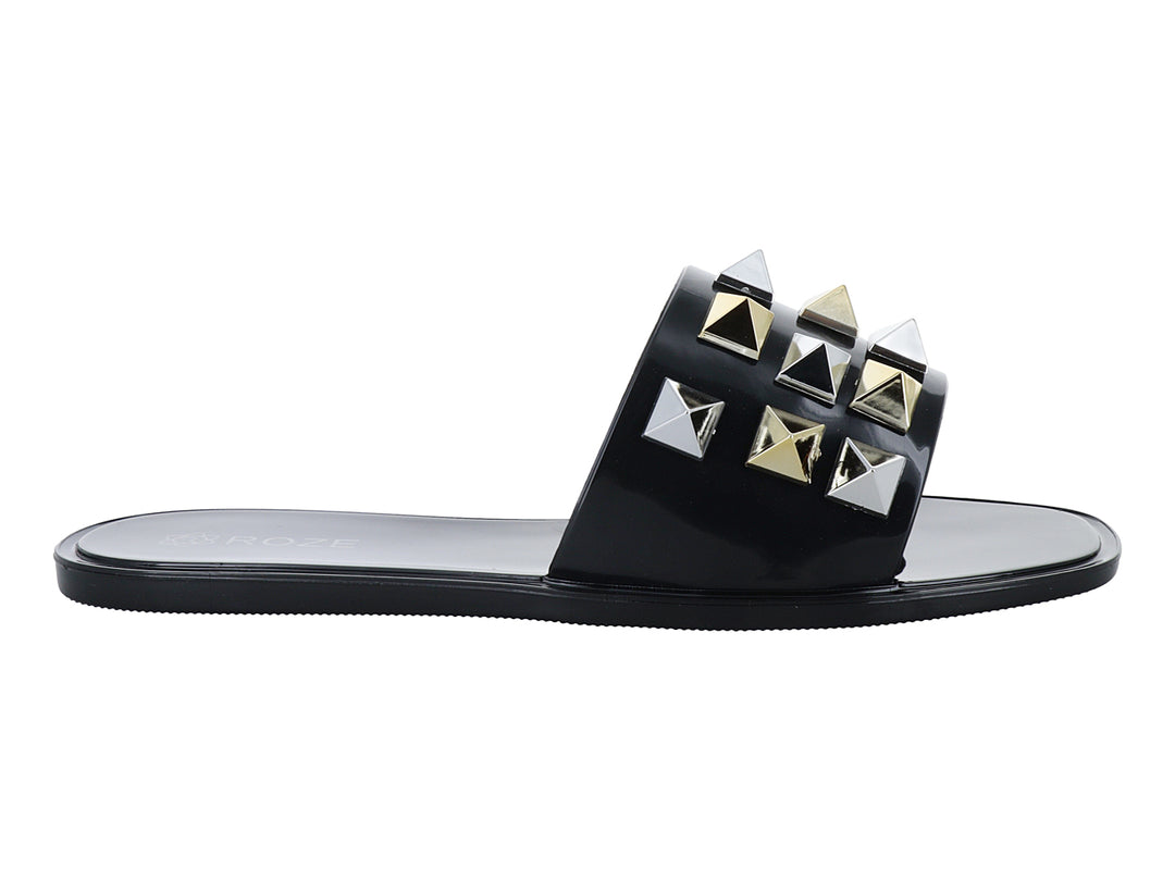 Sandalia slide negra con tachuelas metálicas en forma de pirámide doradas y plateadas.