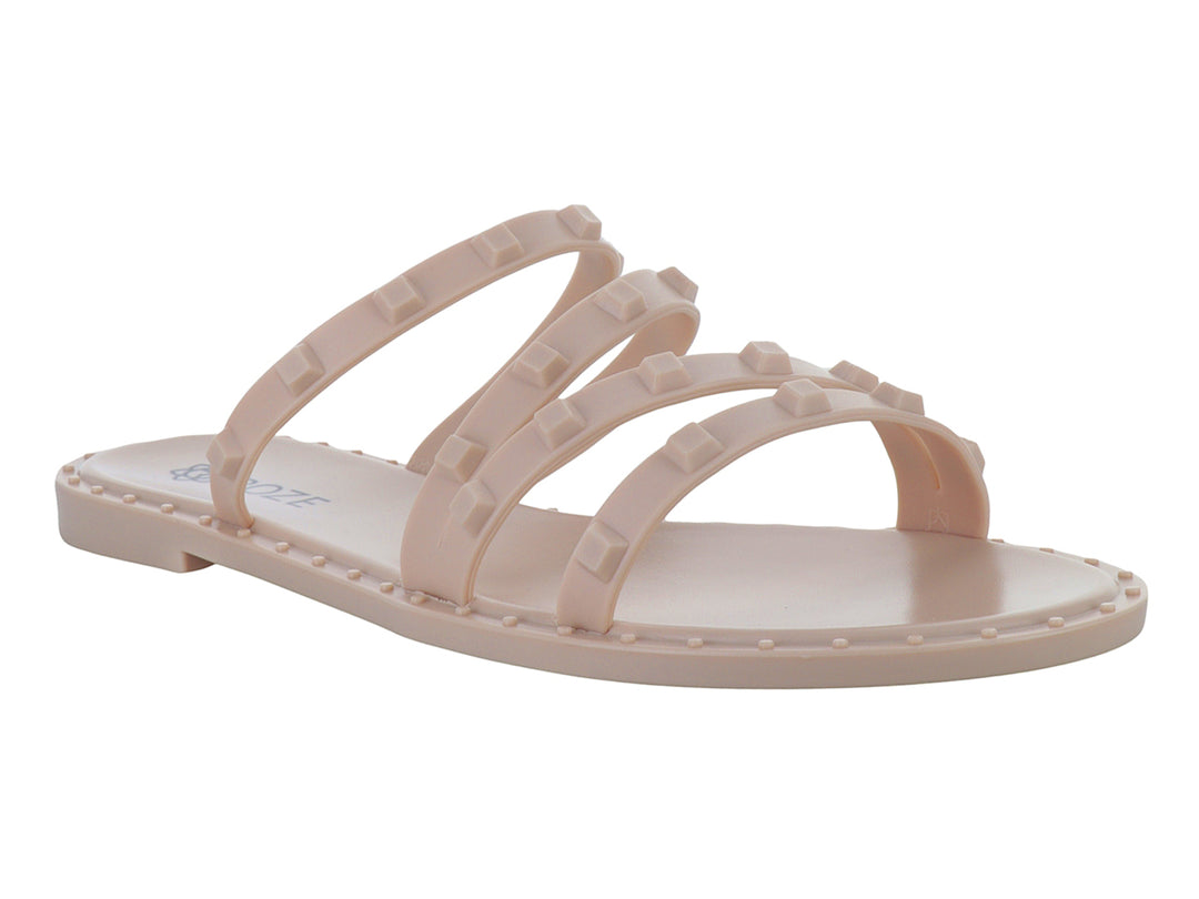 Sandalia plana color nude para niña con tiras decoradas con pequeños relieves cuadrados.