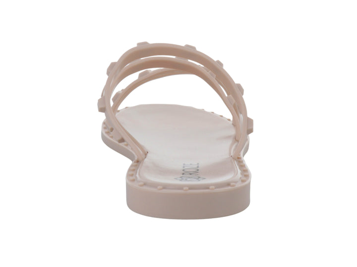 Sandalia plana color nude para niña con tiras decoradas con pequeños relieves cuadrados.