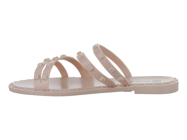 Sandalia plana color nude para niña con tiras decoradas con pequeños relieves cuadrados.