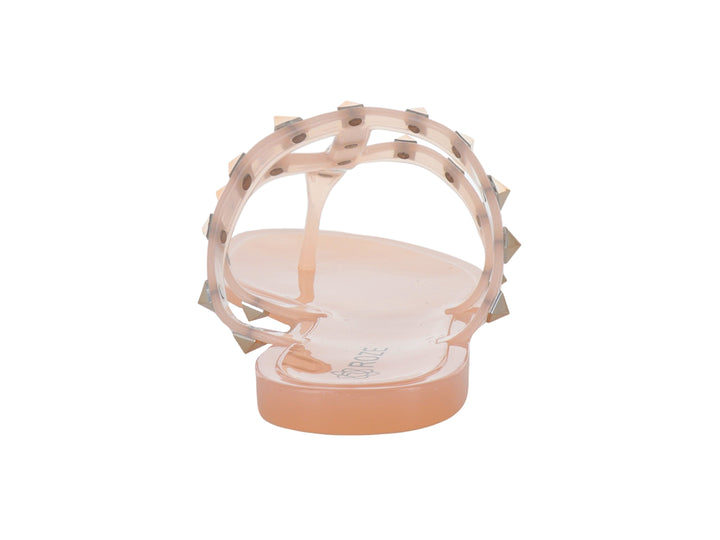 Sandalias color nude con tiras transparentes y tachuelas doradas.