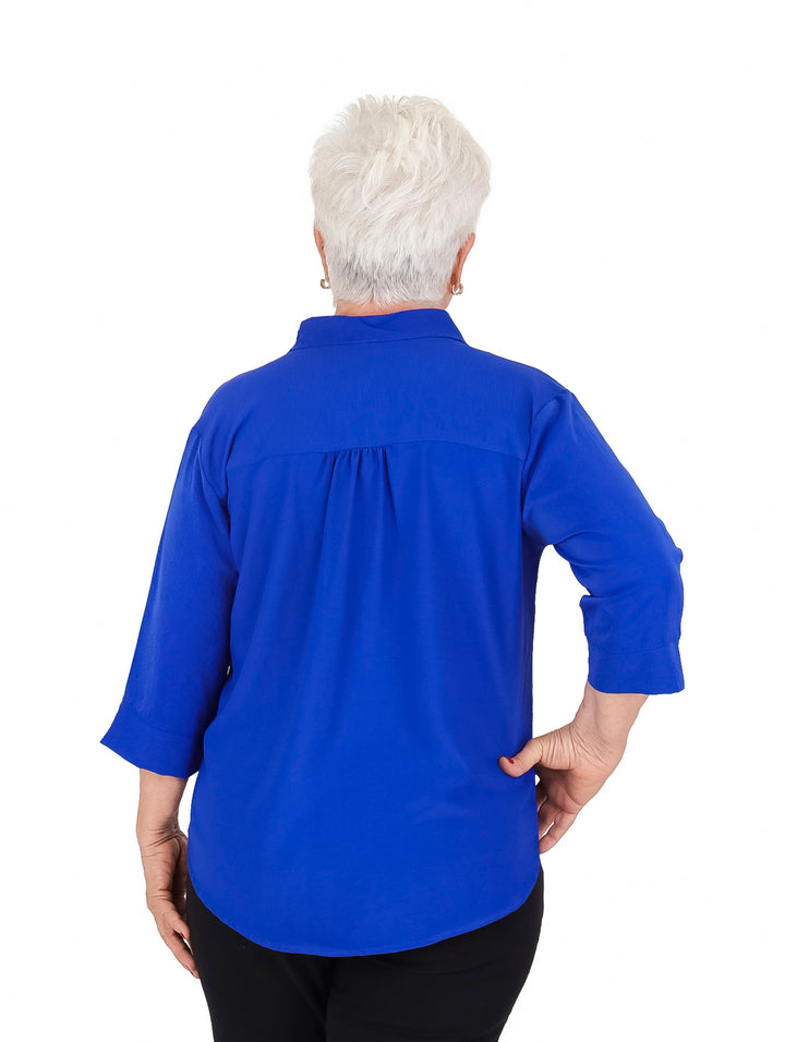 Mujer vistiendo una blusa color azul rey de manga 3/4 y cuello sencillo.