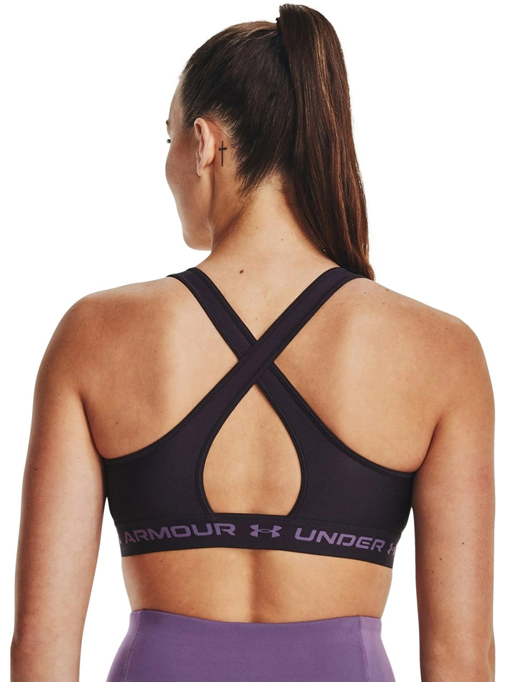 Mujer vistiendo un bra deportivo Under Armour de color morado oscuro.