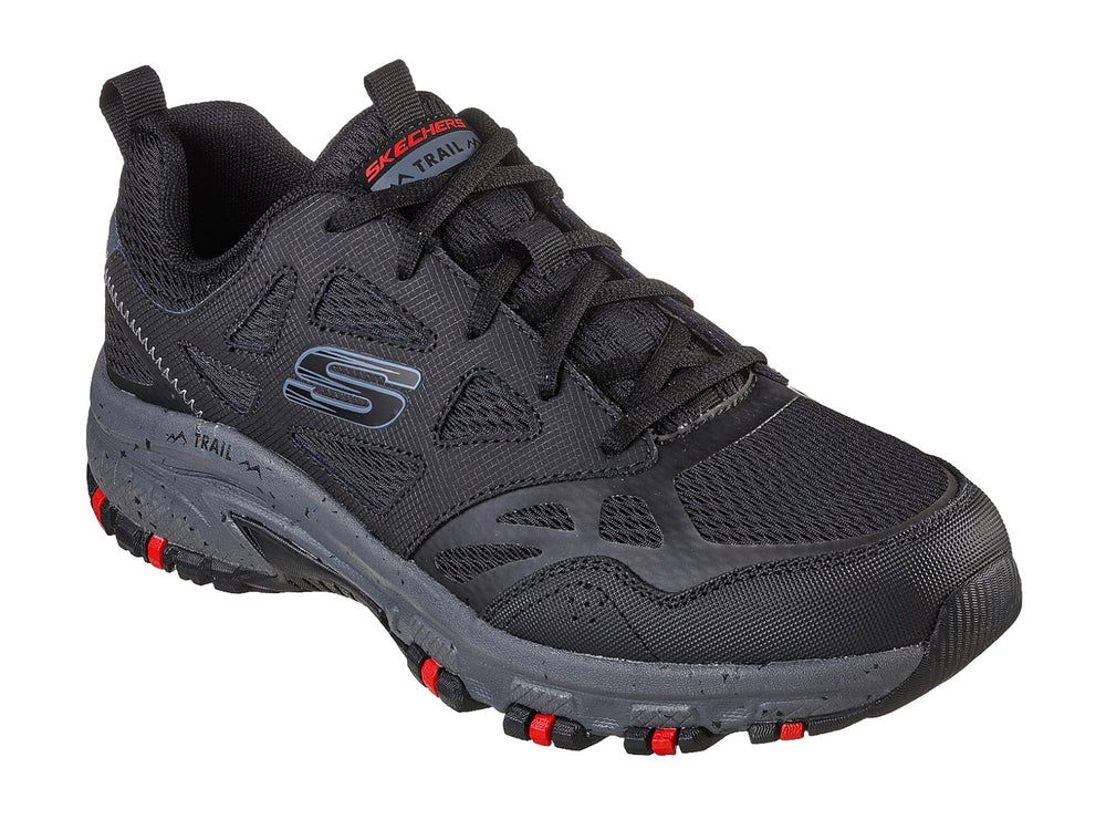 Zapato deportivo Skechers en color negro y gris con detalles rojos en la suela, ideal para actividades de trail.