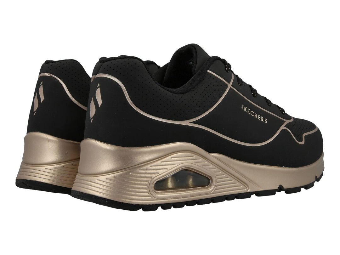 Tenis deportivos Skechers en color negro con detalles y suela en tono oro, con cámara de aire visible.