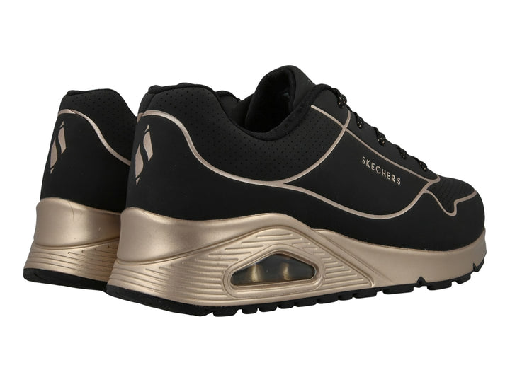 Tenis deportivos Skechers en color negro con detalles y suela en tono oro, con cámara de aire visible.